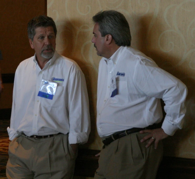 two men stand facing away in front of a wall