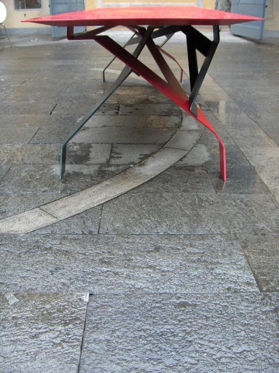 an outside patio with red table and white umbrella on top