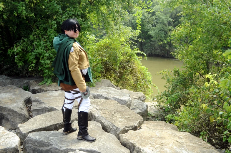 in costume standing at the edge of a rocky cliff overlooking a river