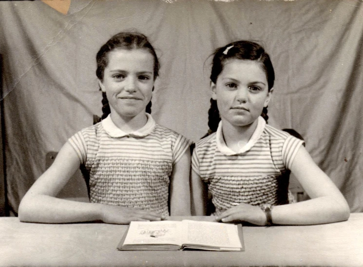 two girls are sitting at a table and reading