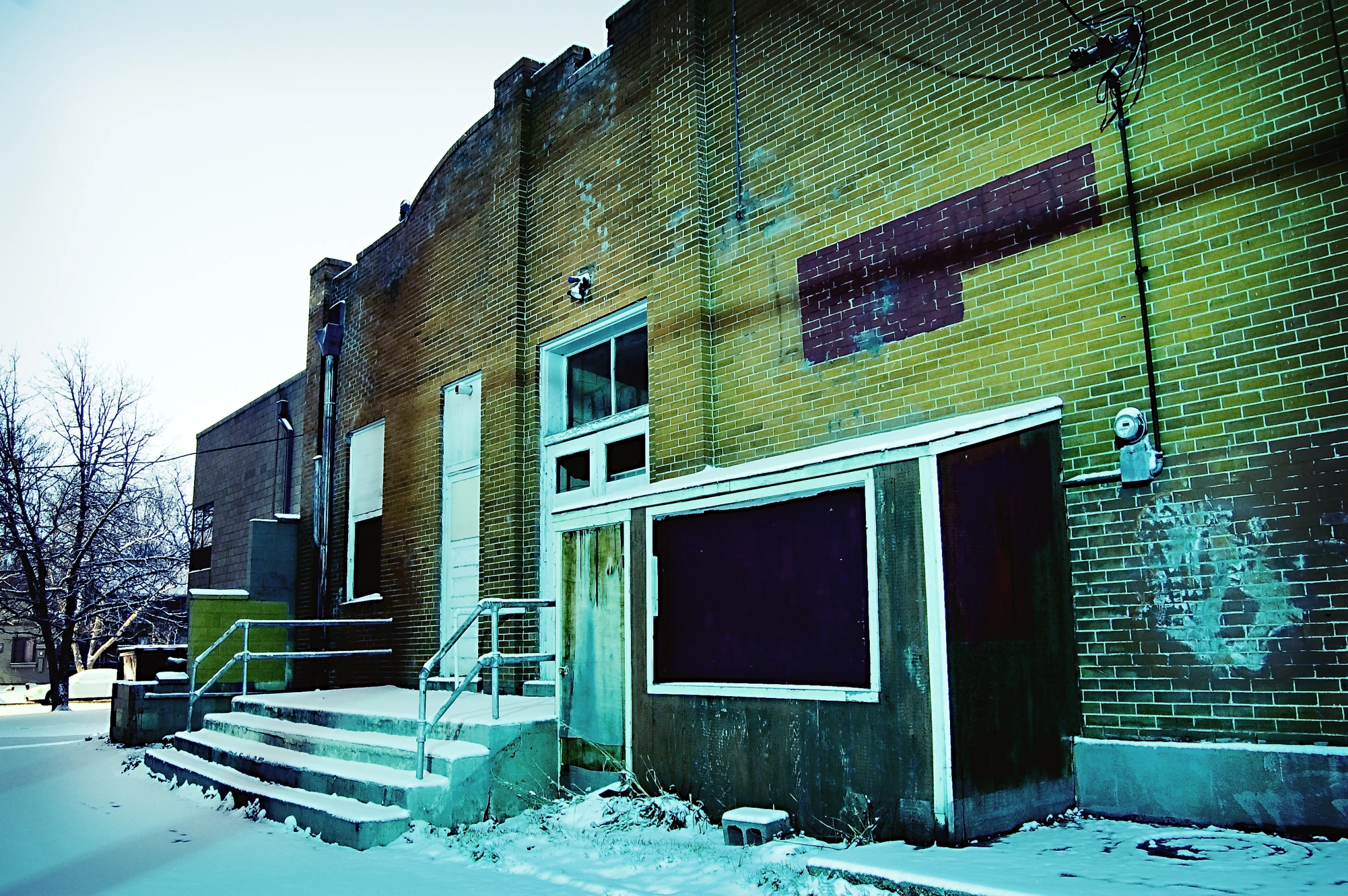 an abandoned building on the side of a snowy street