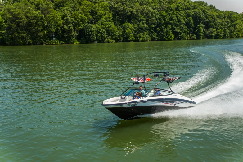 a boat traveling along the water with trees in the background