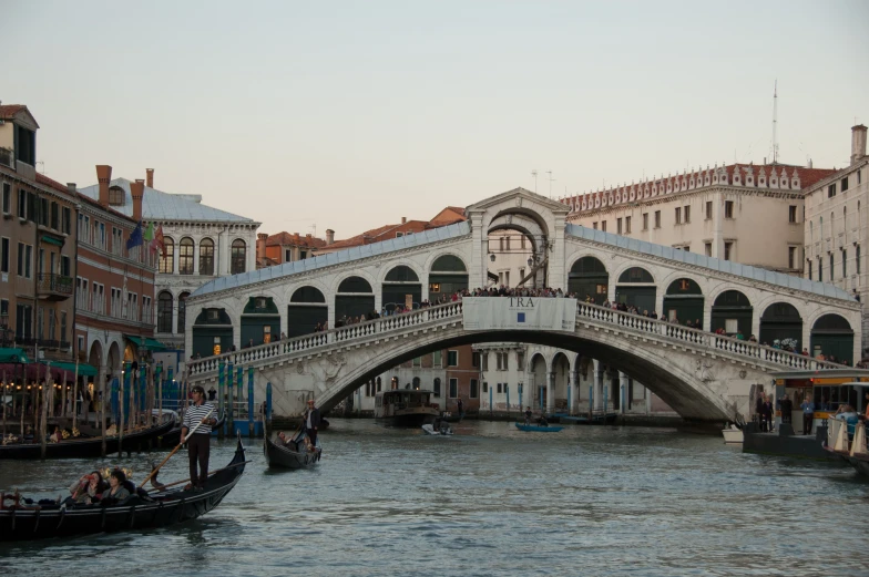 boats ride in the water under a bridge