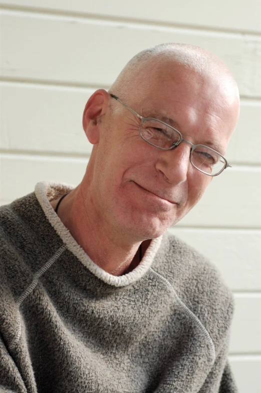 an old balding man wearing glasses and a sweater