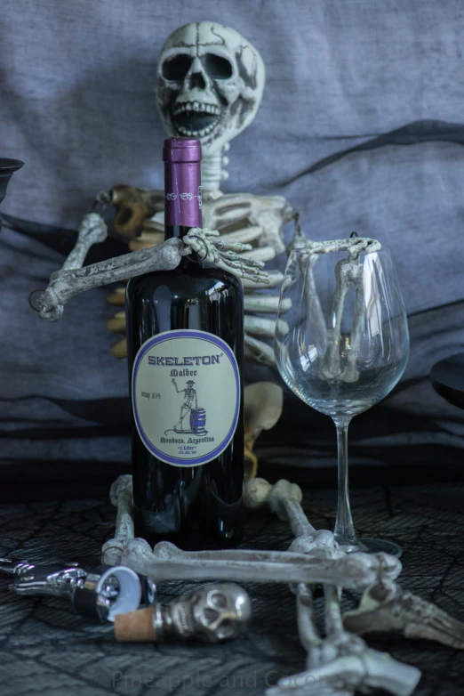 skeleton figurine holding a bottle of wine and a glass