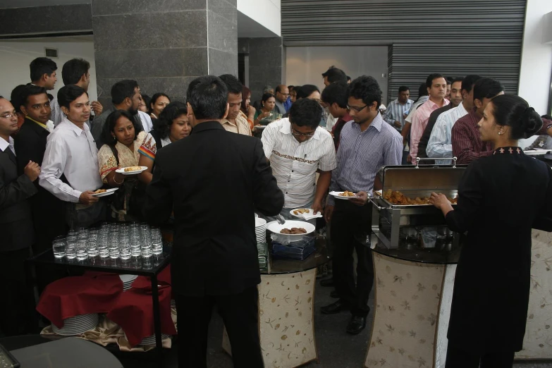 several people standing around eating and standing around