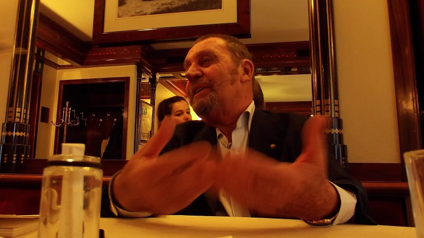 a man with his hands in the air as he eats at a restaurant