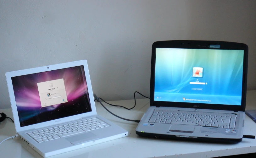 an open laptop computer next to an open mac book on a white desk