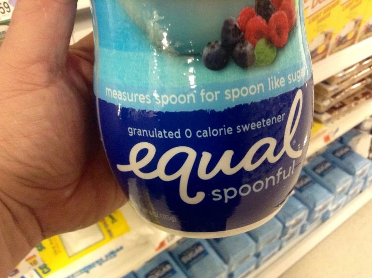 a person holding a jar of fruit on a grocery aisle shelf