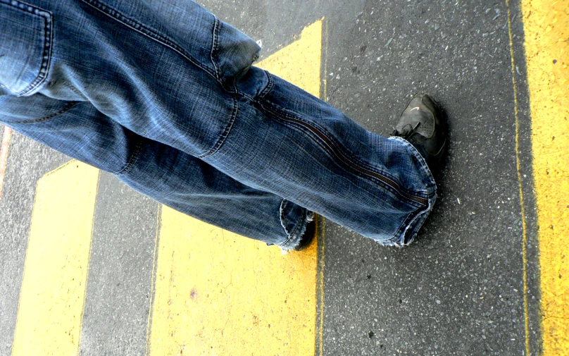 a man is standing on a paved road in front of some blue jeans