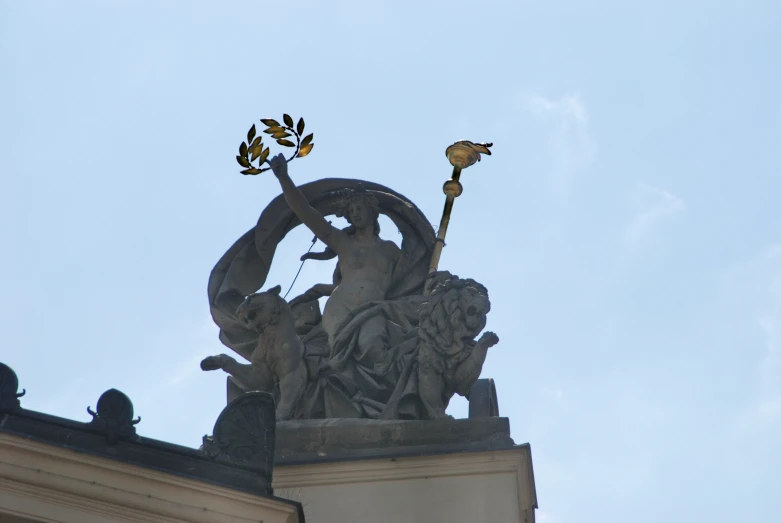 a statue holding three flowers and two angel statues is seen from below