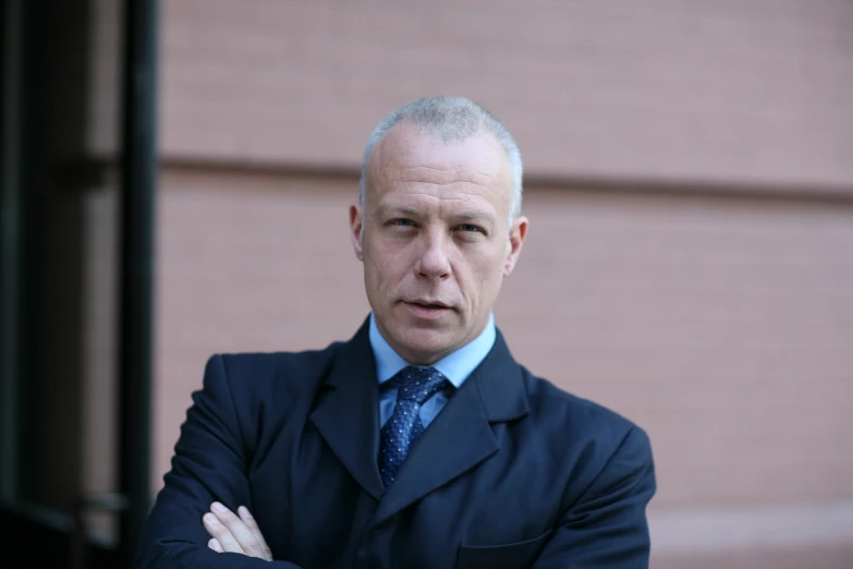 a man in a blue suit stands with his arms crossed