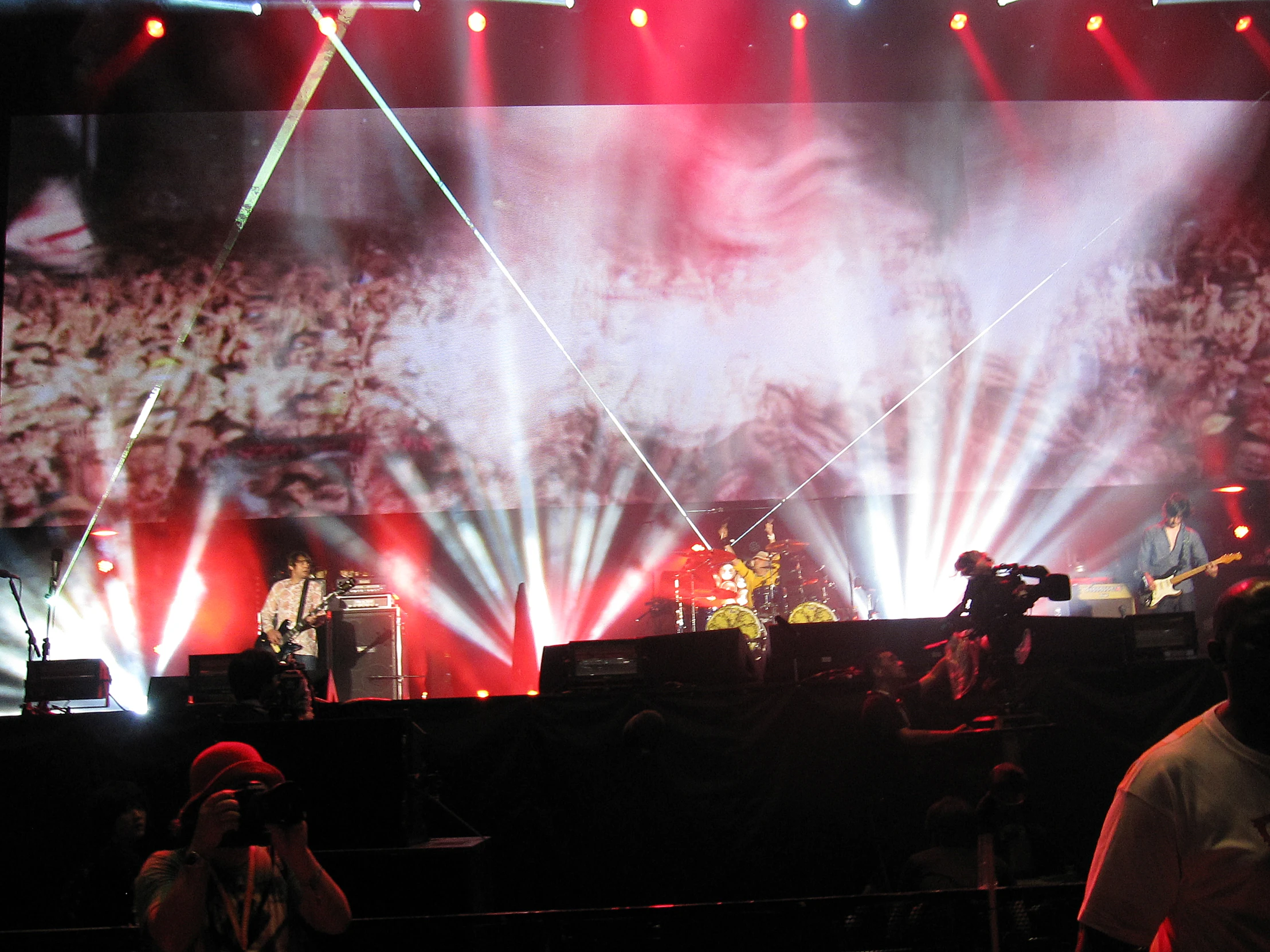 several people are sitting at a stage as musicians play on it