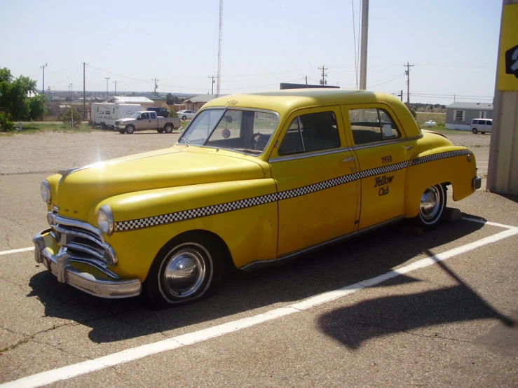 a yellow vintage car parked in the parking lot