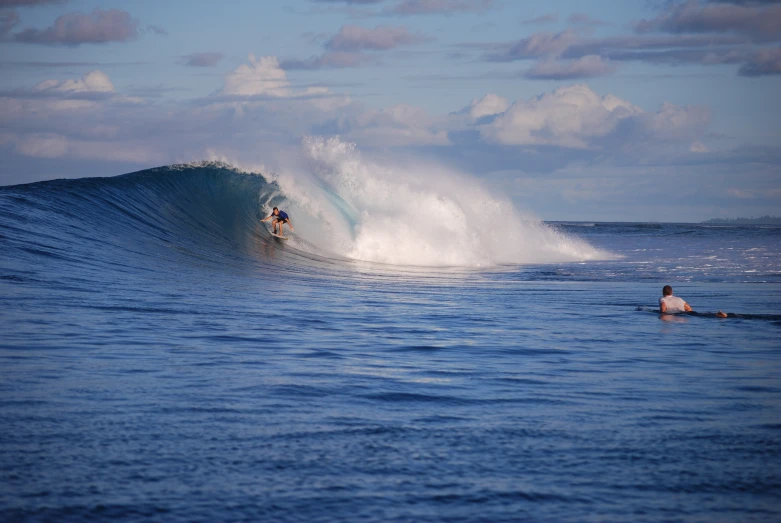 two people are surfing on an ocean wave