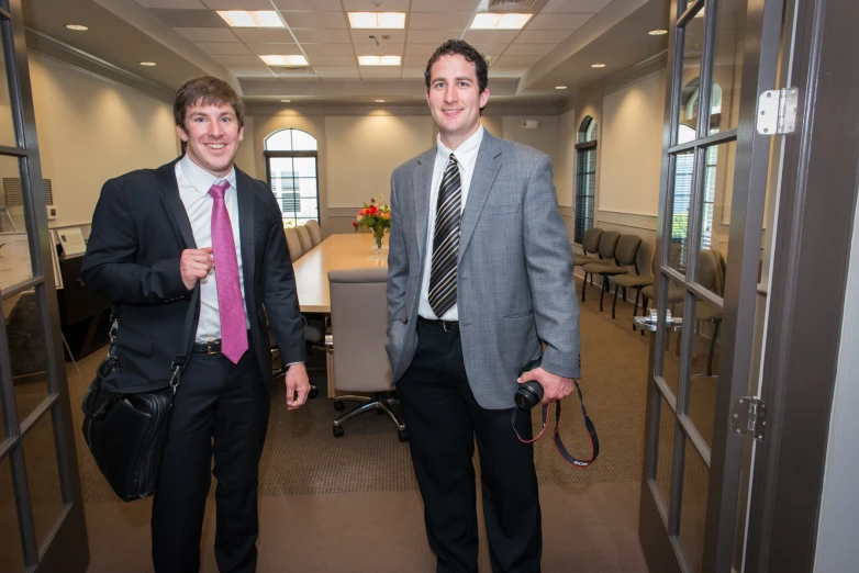 two men dressed in suits and ties in an office