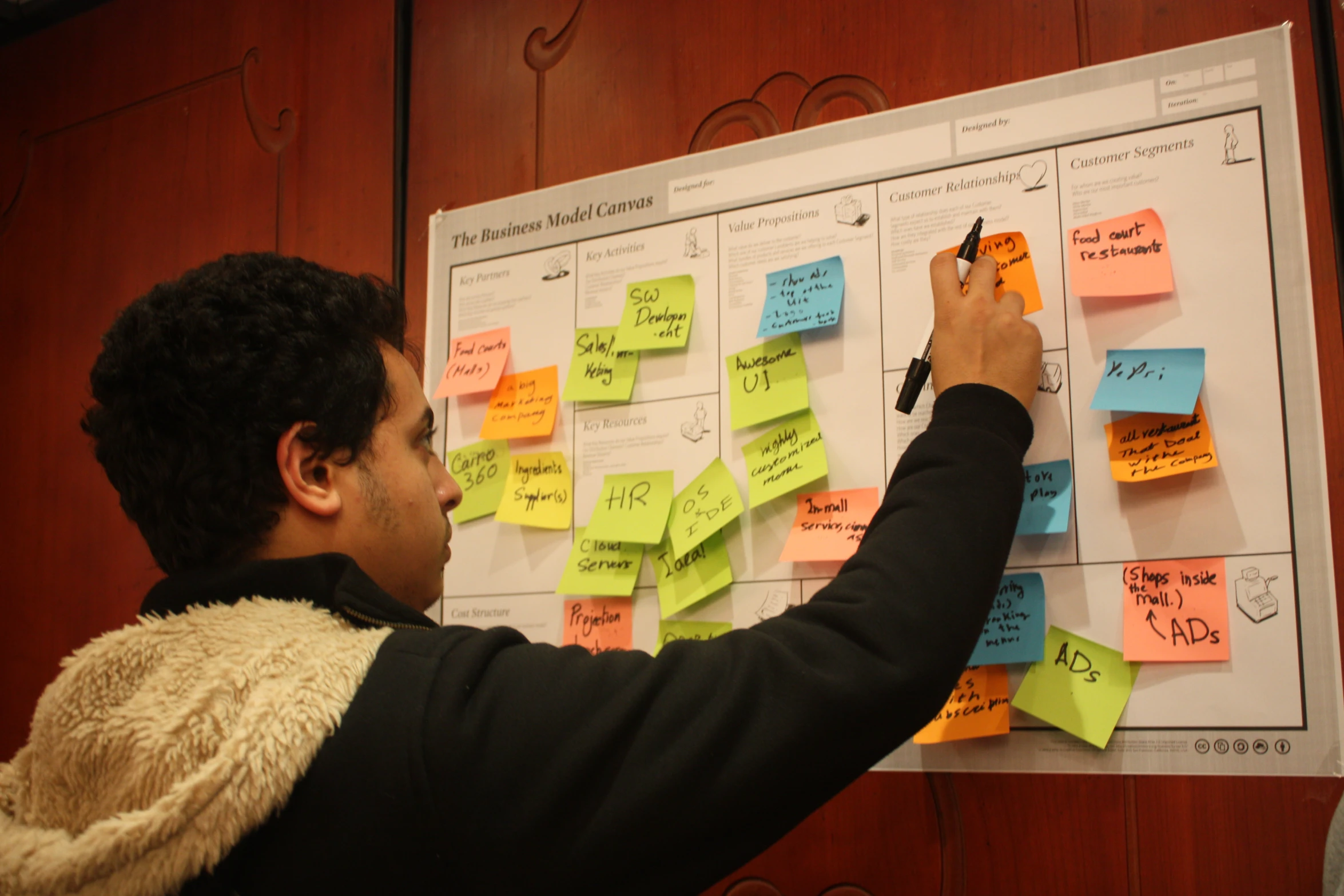 a man taking notes from sticky notes on a bulletin board