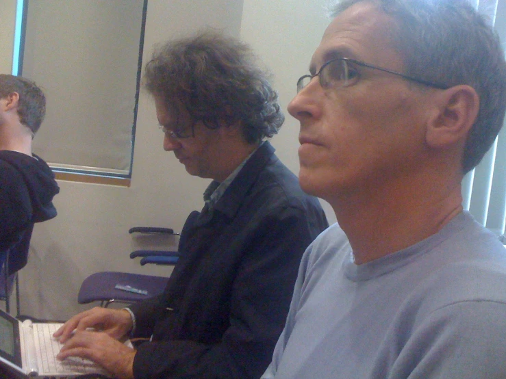 two men in suits sitting down with laptops