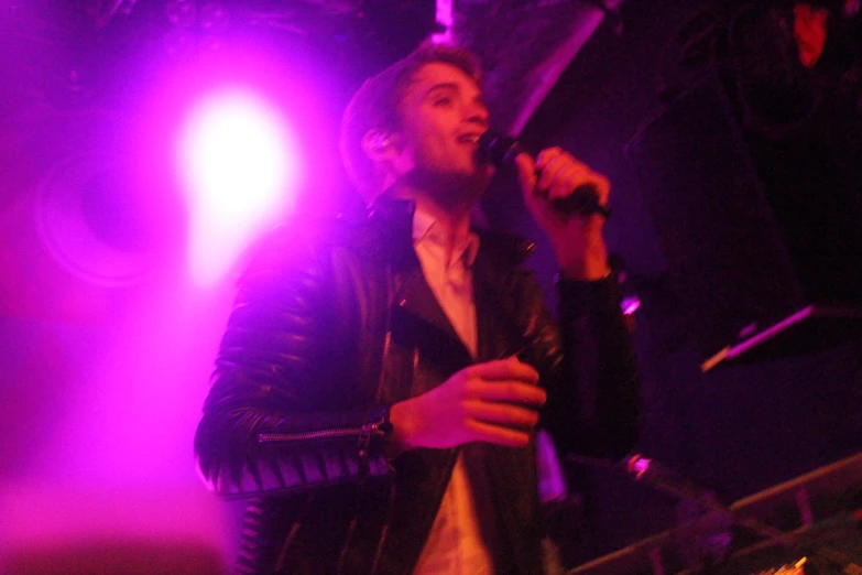 a man singing in a microphone in front of lights