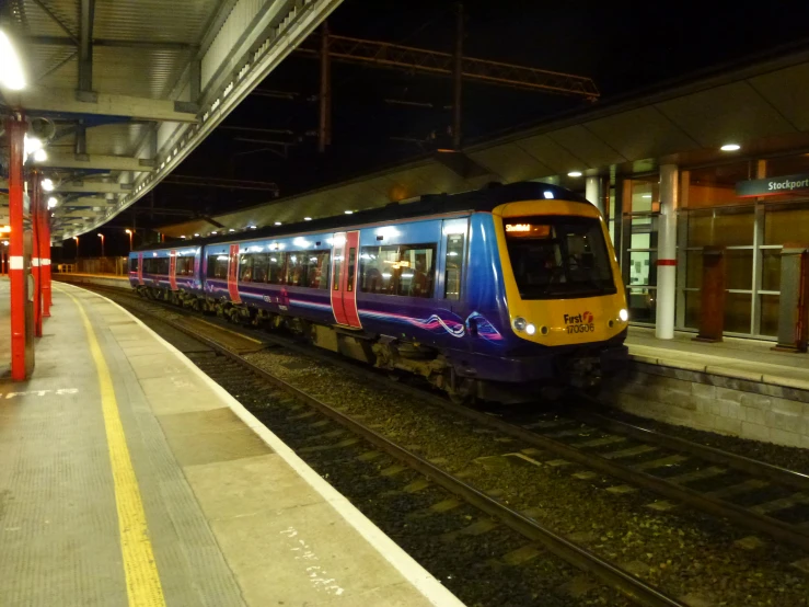 a purple and yellow train pulling into a station