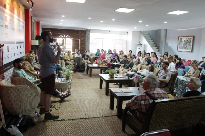 a man speaks to a group of people in a room