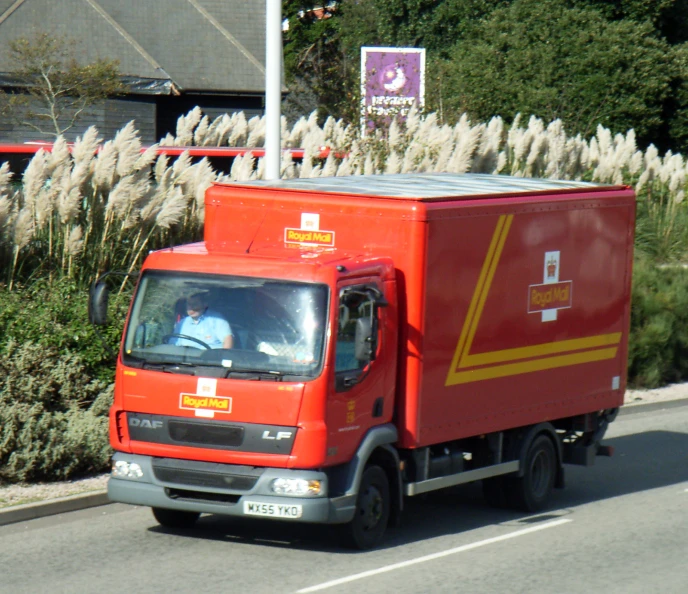 the small red truck is carrying materials down the road