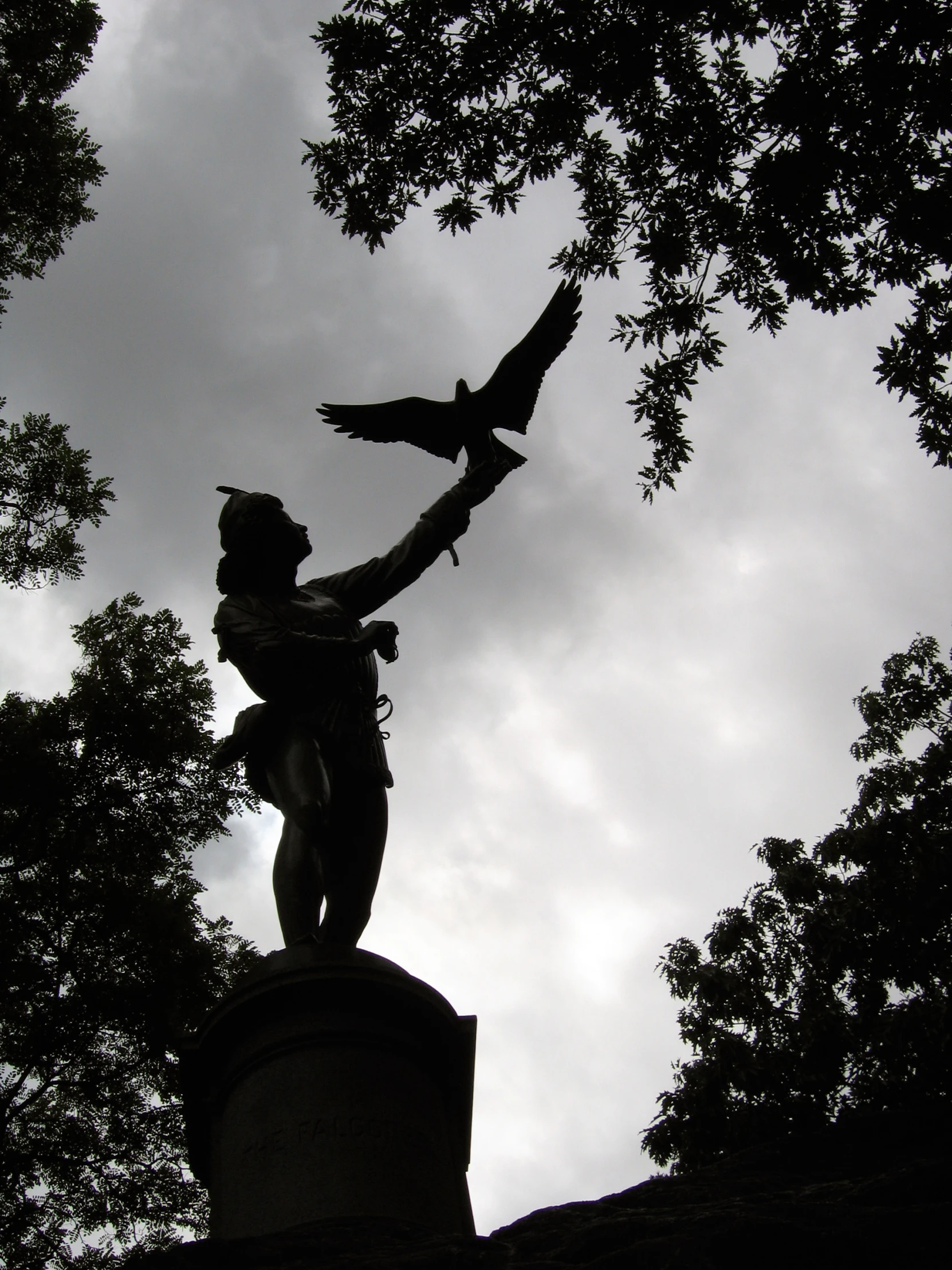 a statue in a park with trees growing behind