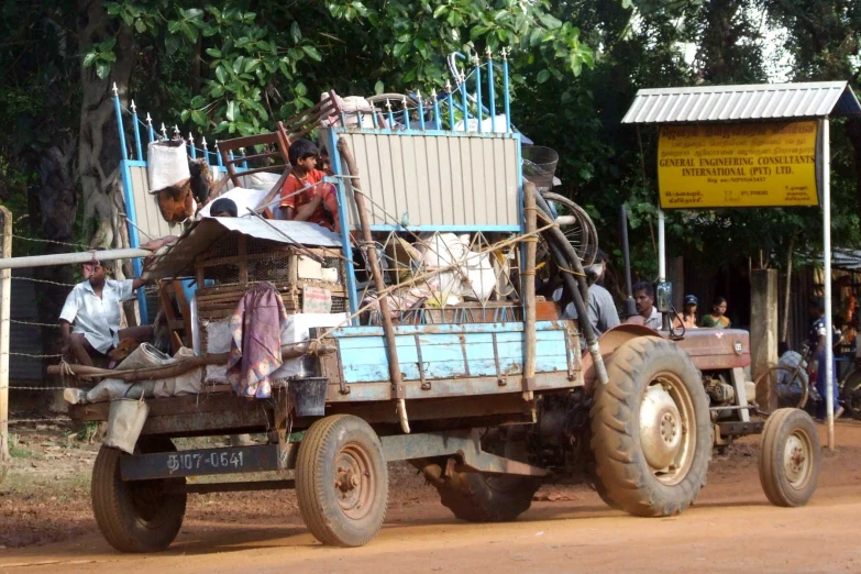 a big truck full of people moving down a dirt road