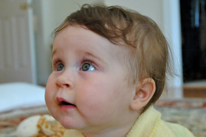 an adorable young child sitting on the floor and looking at soing with a frown on her face