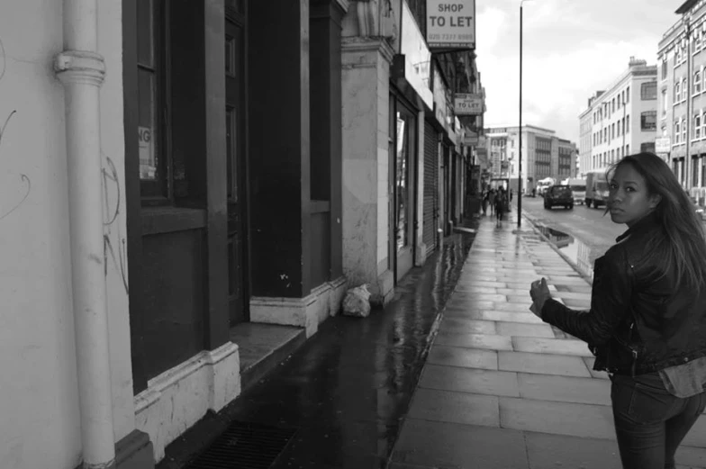 a young woman standing on a wet street holding an umbrella