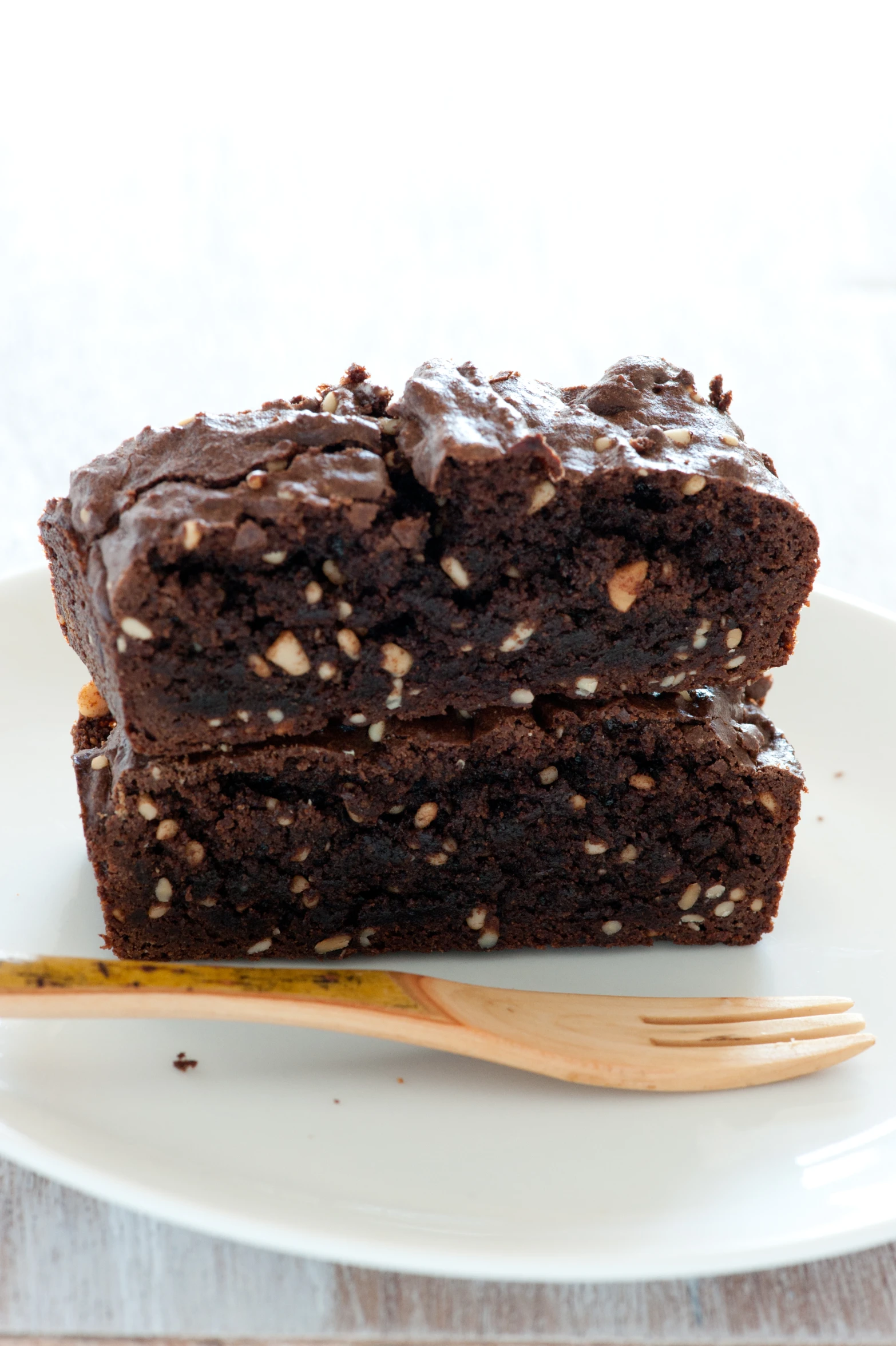 two pieces of brownie sitting on top of a plate with a plastic fork