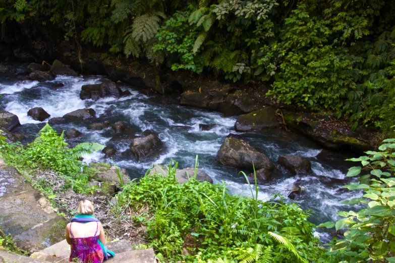 a person sitting on steps above water near rocks