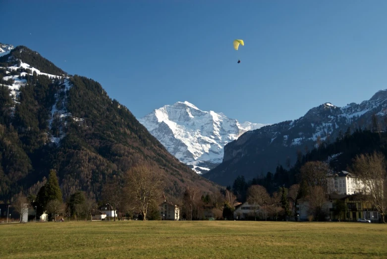 the people are flying kites near the mountain tops