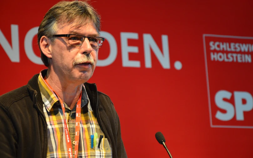 an older man with glasses giving a speech at a podium