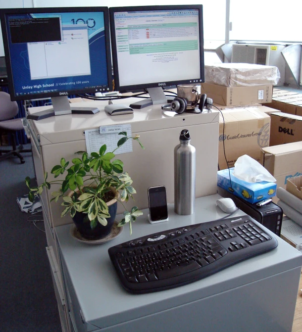 an office workstation with many computers, a desk top, and boxes