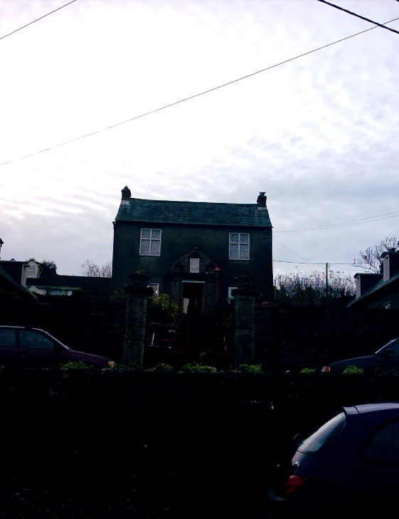 a gray house sits at the corner of a fence