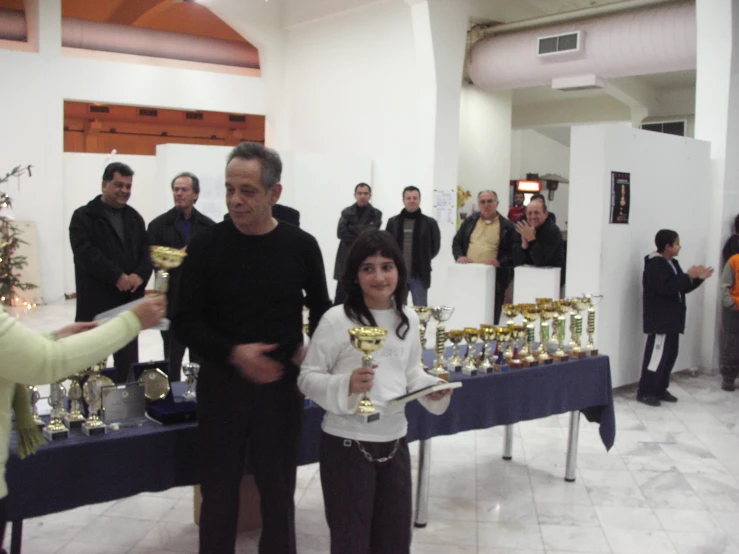 two women and one man holding trophy cups