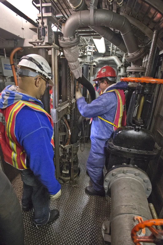 workers looking into the engine of a large metal machine