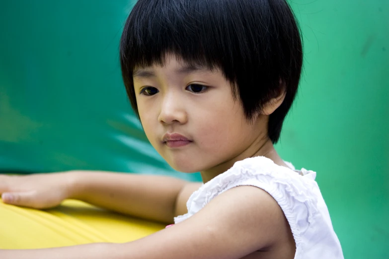 a small child with a black hair and a white top