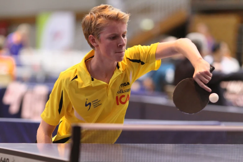 a boy is playing table tennis on a sunny day