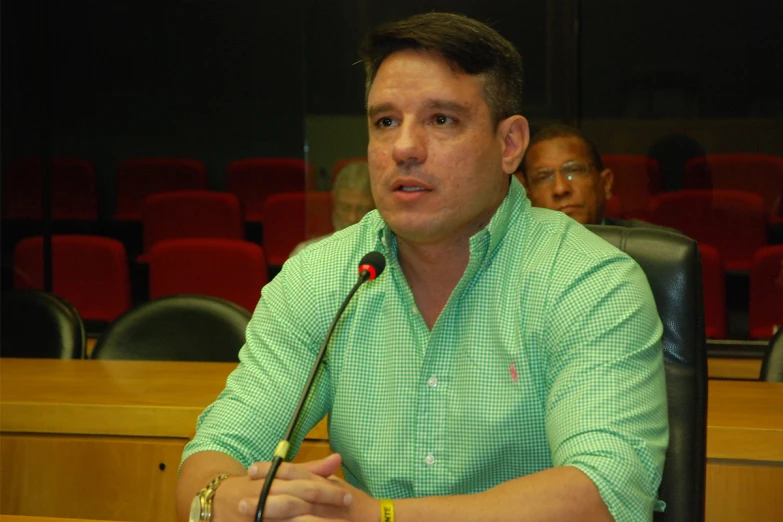 a man is sitting at a table in front of a microphone