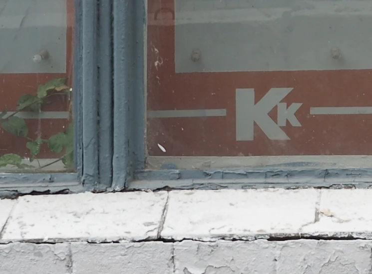 a window with a red and gray sign and brick wall