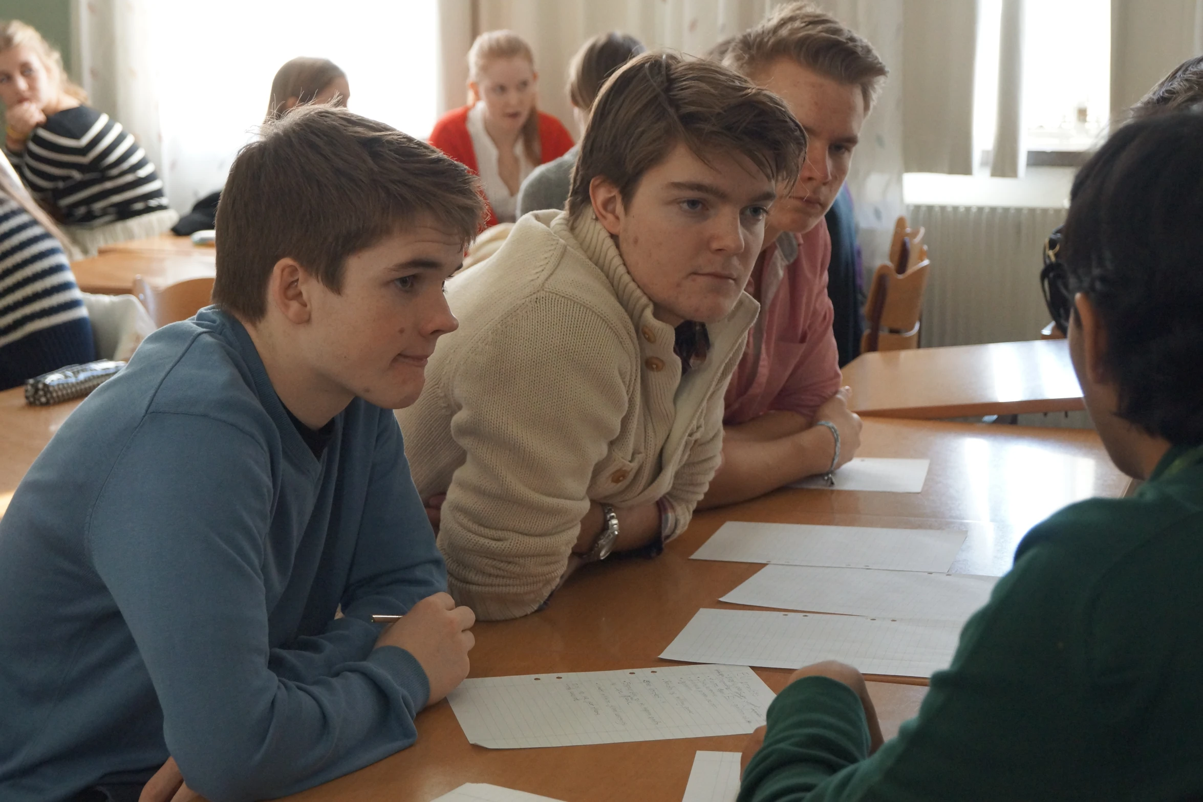 a group of young people sitting at a long table