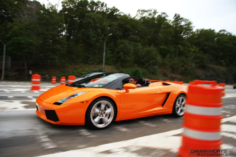 the orange sports car is driving down the road