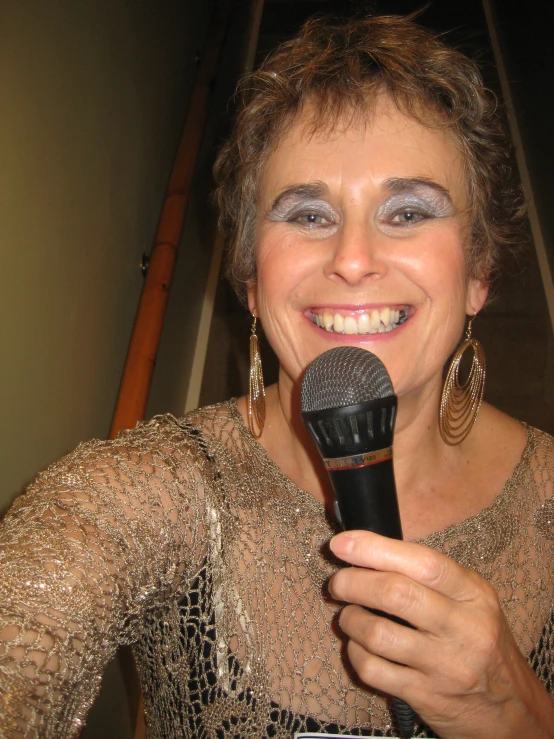 a woman wearing silver makeup and holding a microphone