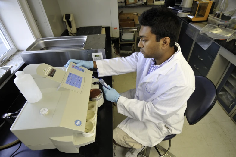 man in lab coat using a machine to examine an item