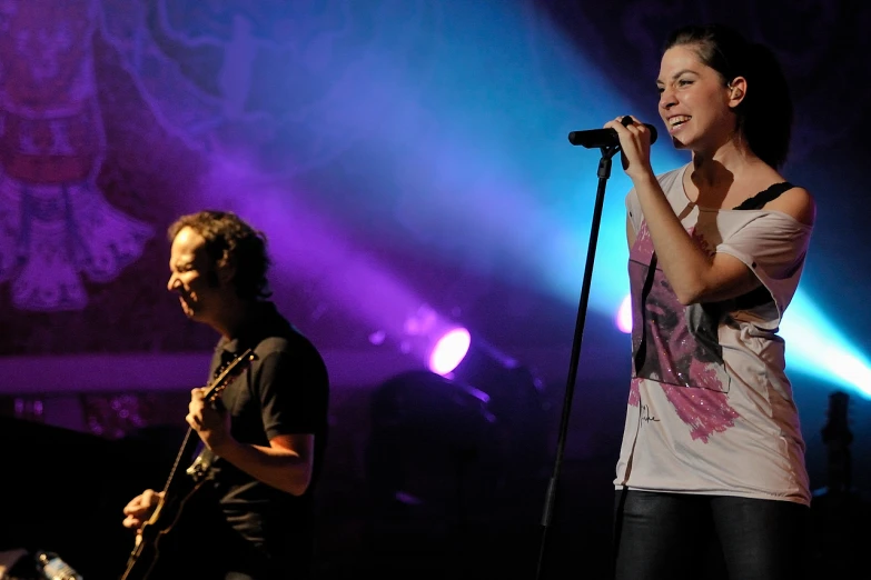 two people sing on stage at a concert