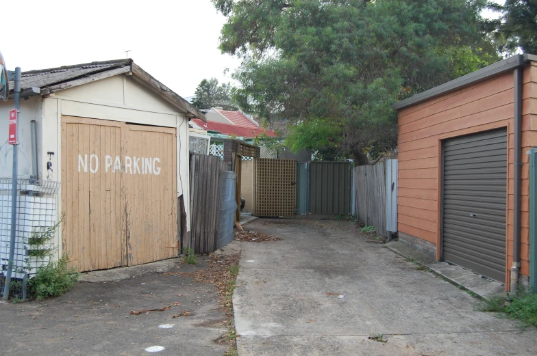 a street with boarded up sheds and a no parking sign