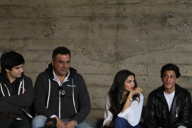 a group of young people sitting on a bench next to a stone wall