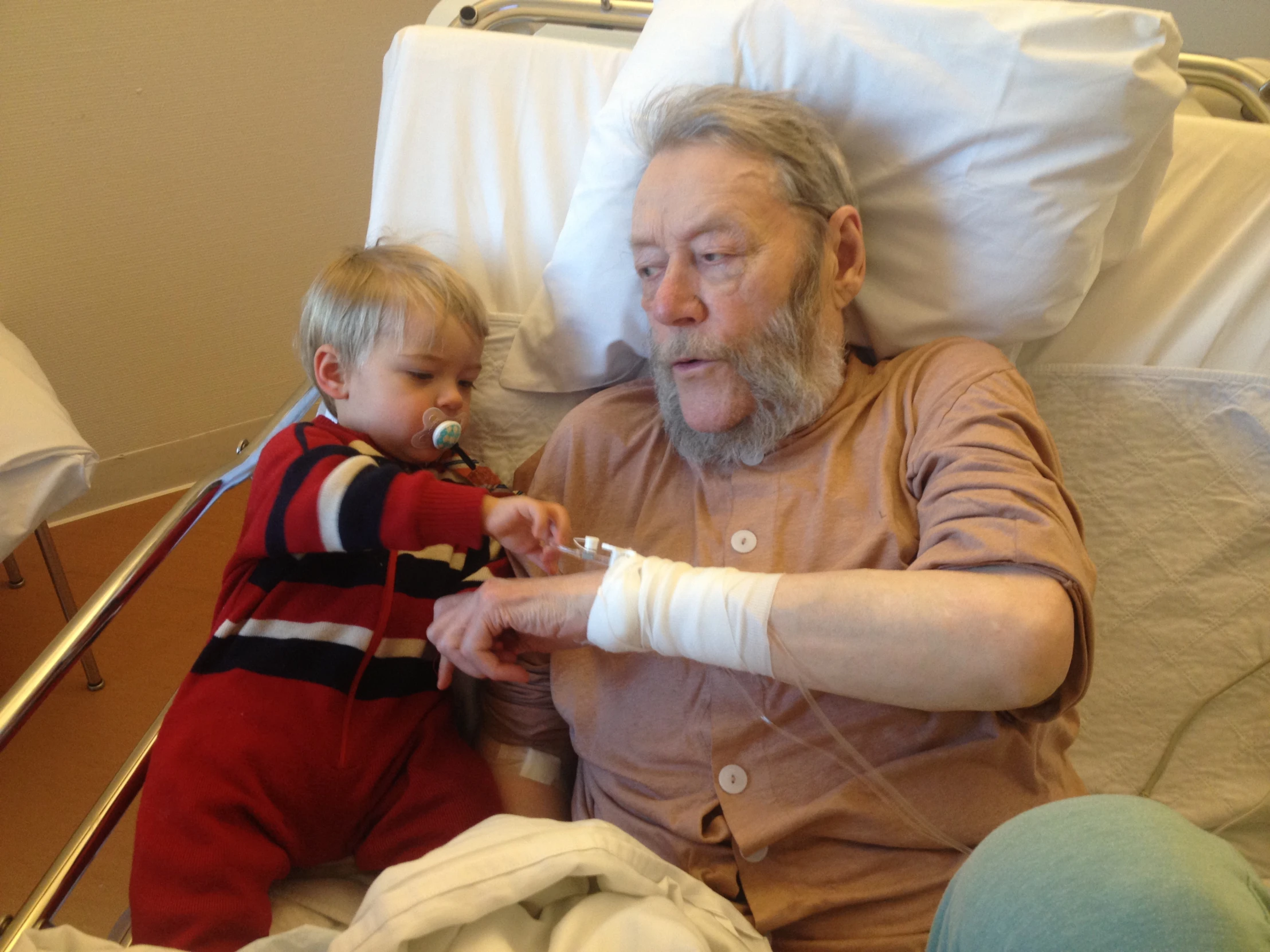 the elderly man is sitting in bed next to a baby